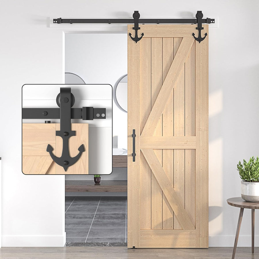 Wooden sliding barn door with black hardware on a white wall.