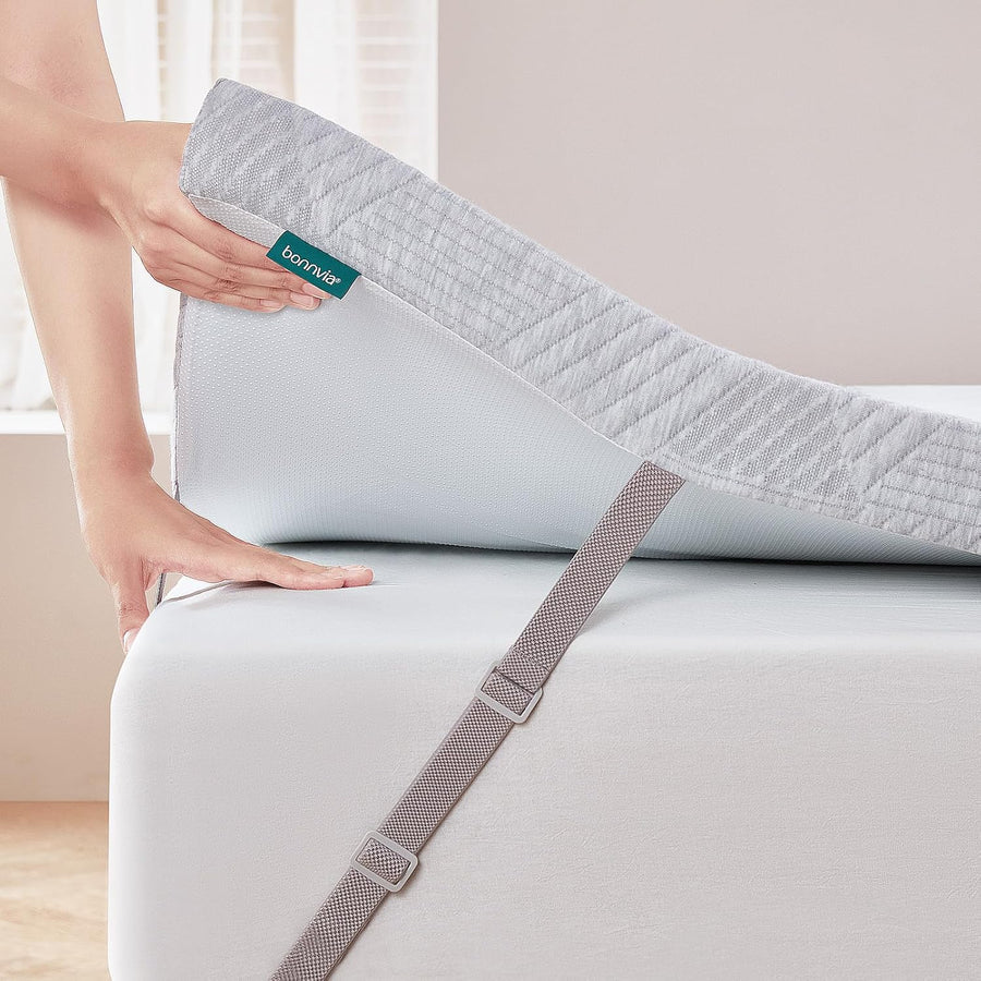 Person adjusting a fitted sheet on a bed with a Bonmaté label.