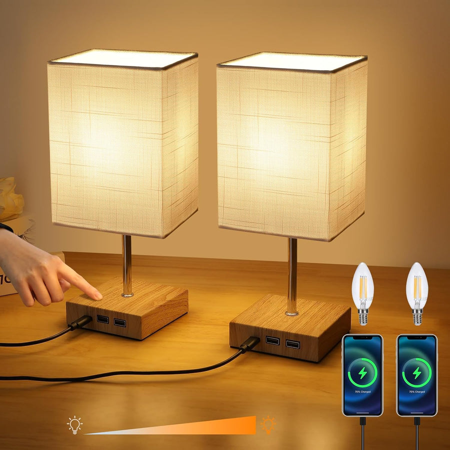 Two table lamps with wooden bases and fabric shades, connected to a power source, on a wooden surface.
