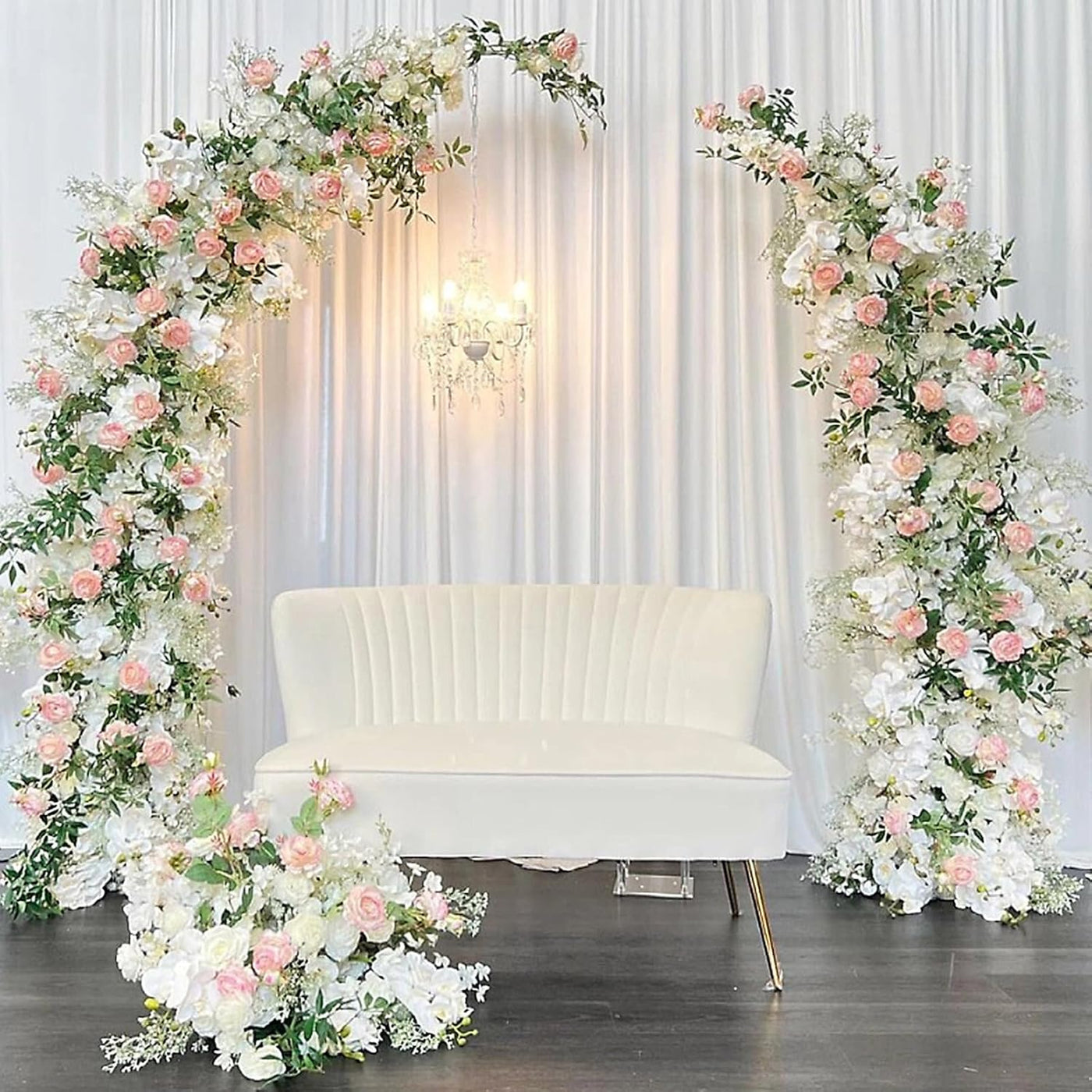 Decorative floral arches with pink and white flowers surrounding a white couch.