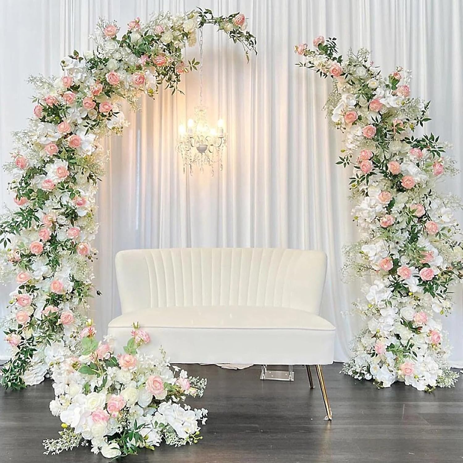 Decorative floral arches with pink and white flowers surrounding a white couch.