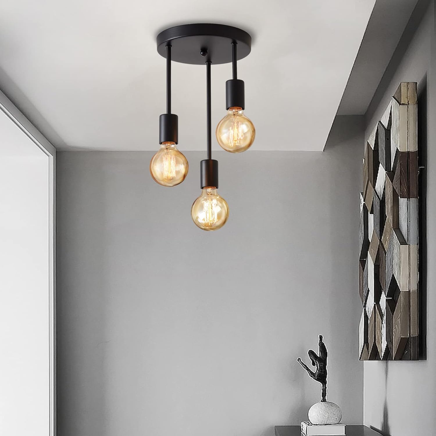 Modern ceiling light fixture with three bulbs in a room with a decorative wall piece.