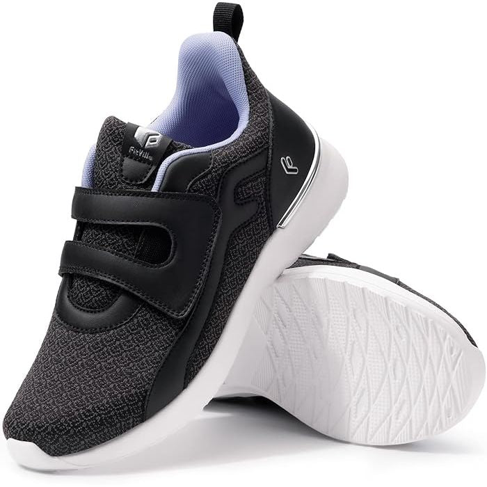 A pair of FitVille women's sneakers with a wide fit design, featuring a black leather and canvas outer material, a Velcro closure, and a light-colored sole.