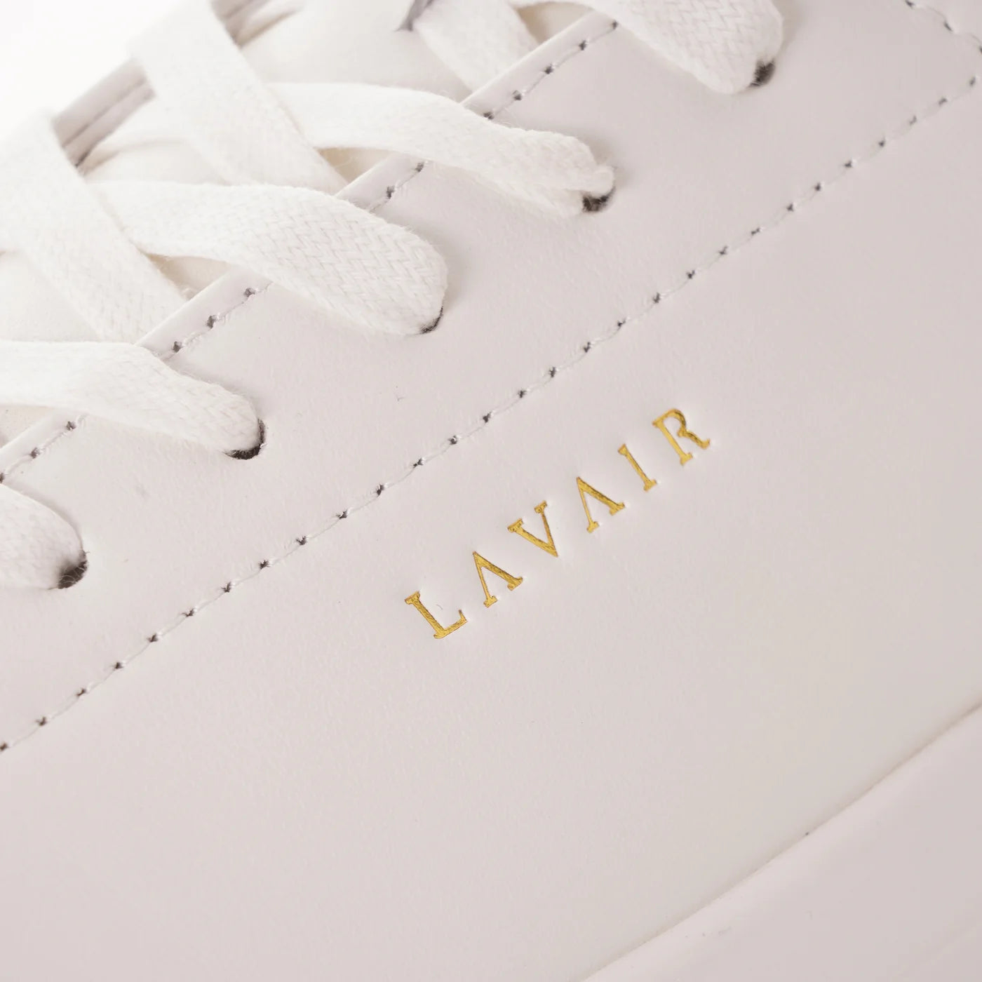 Close-up of a light pink sneaker with 'LAVAIR' branding on a matching background