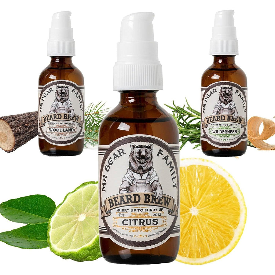 Three bottles of Mr. Bear Family beard oil in citrus scent, with jojoba, argan, and almond oil, displayed with lemon and lime.
