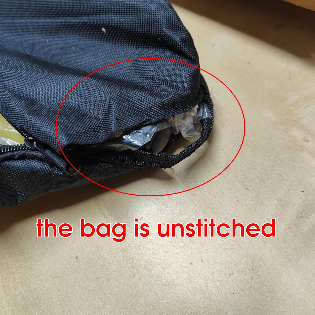 Unstitched black bag on a beige surface with red circle and text.