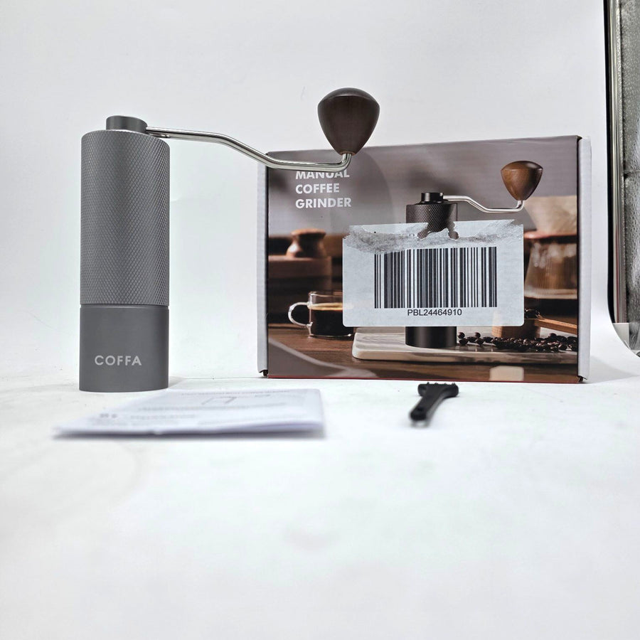 Manual coffee grinder with COFFA branding on a white surface, next to its packaging.