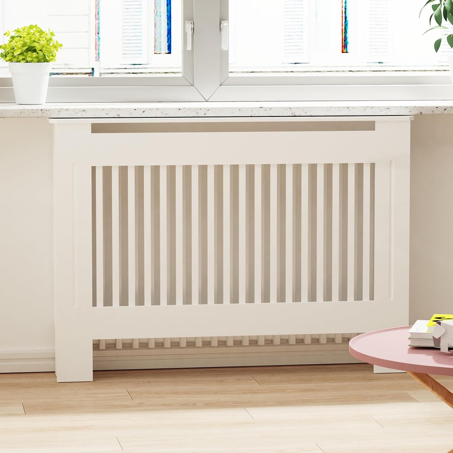 White radiator in a room with a window and small table.