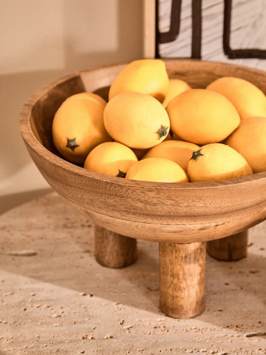Wooden bowl filled with lemons on a stone surface