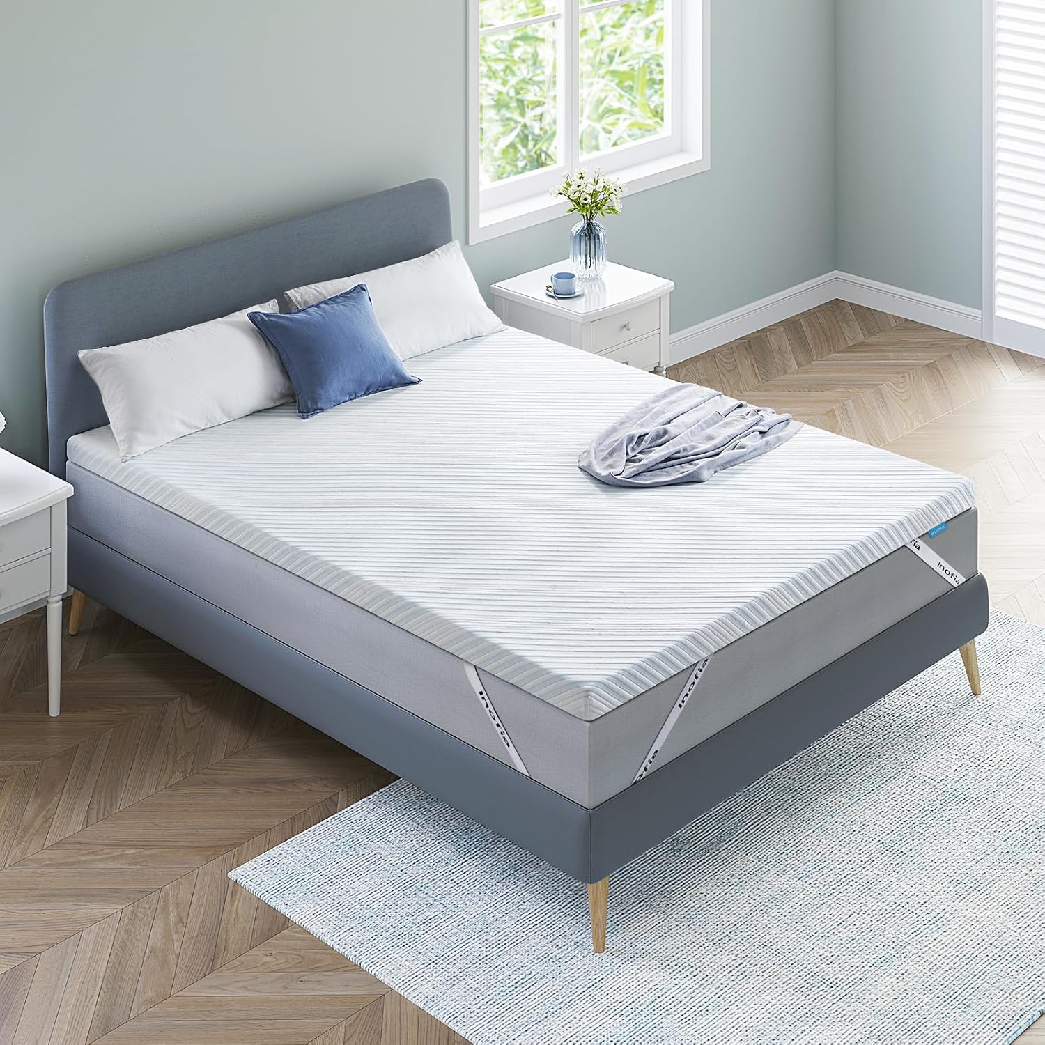 Mattress on a bed in a room with a window and side tables.
