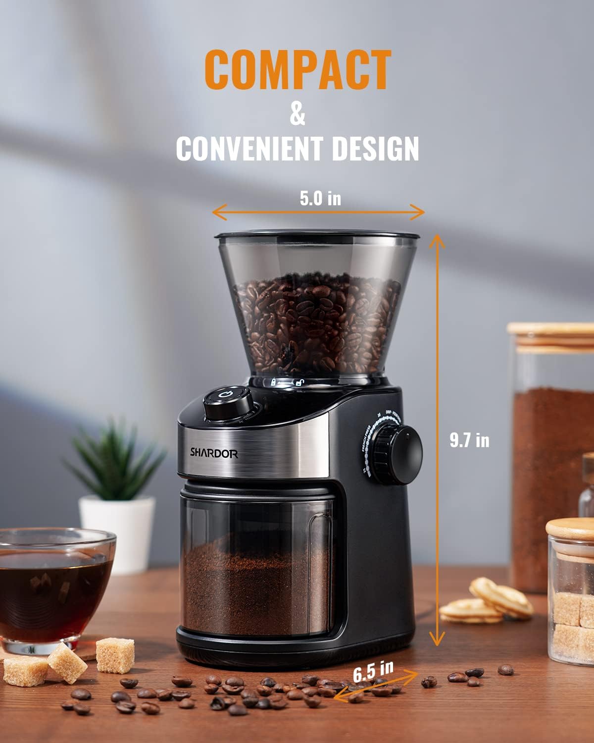 Coffee grinder with dimensions labeled on a wooden surface, surrounded by coffee beans and a cup of coffee.