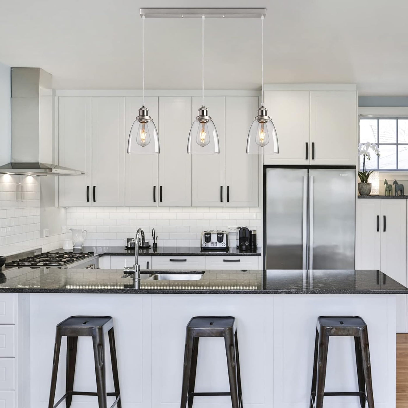 Modern kitchen with white cabinets, stainless steel appliances, and black countertops.