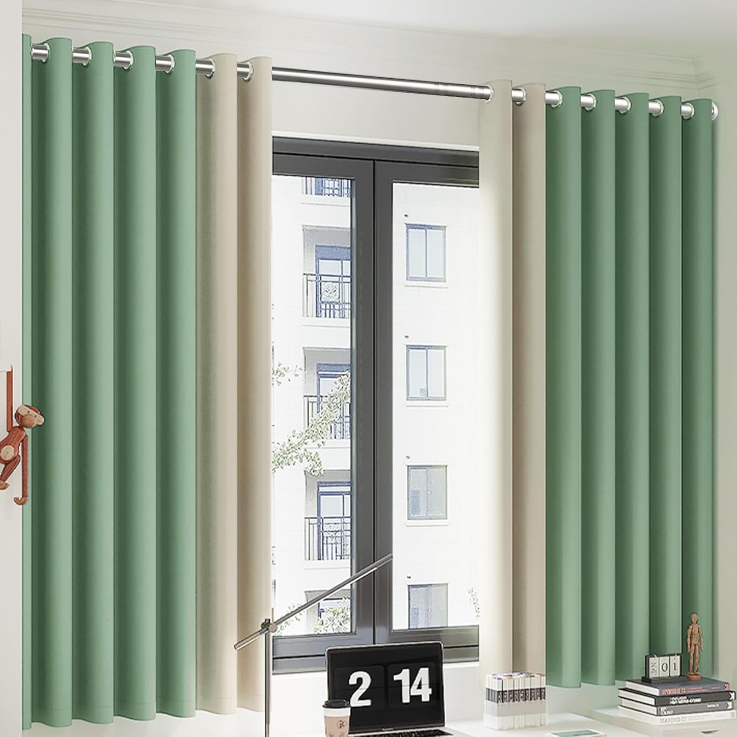 Green and beige curtains on a window with a desk and decor items in the foreground.
