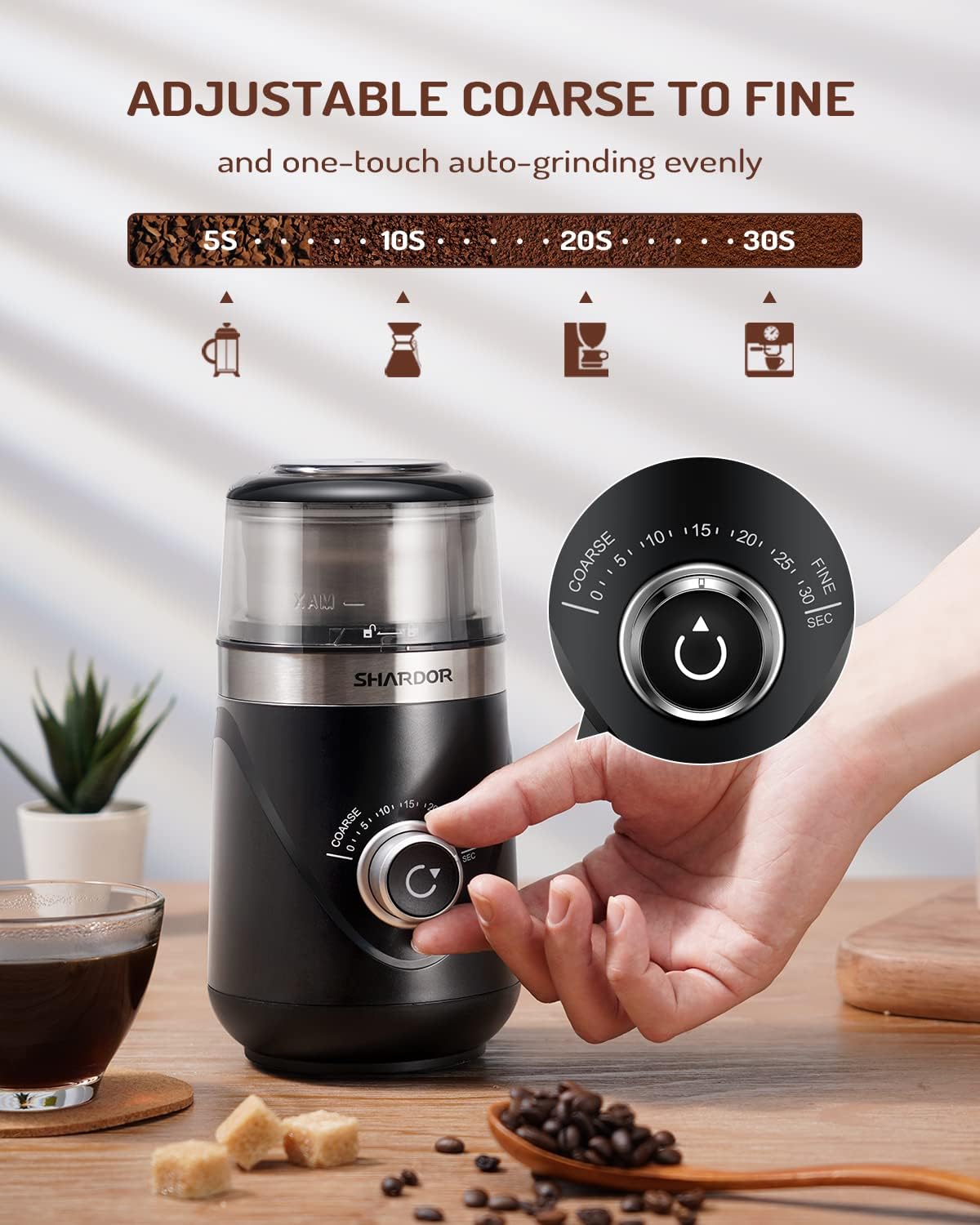 Coffee grinder with adjustable settings on a wooden surface with coffee beans and a glass of coffee.