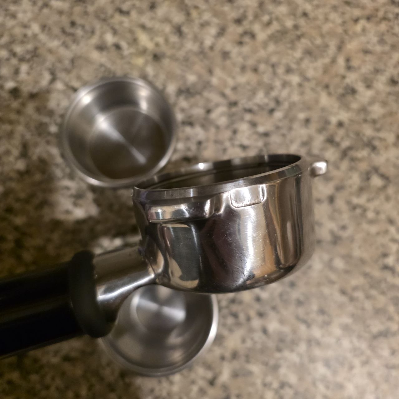 Metal espresso portafilter on a granite countertop