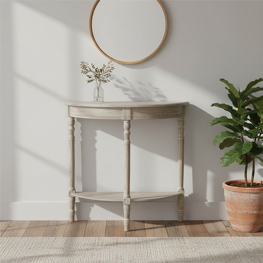 Corner console table with a plant and mirror in a room with wooden flooring and white walls.