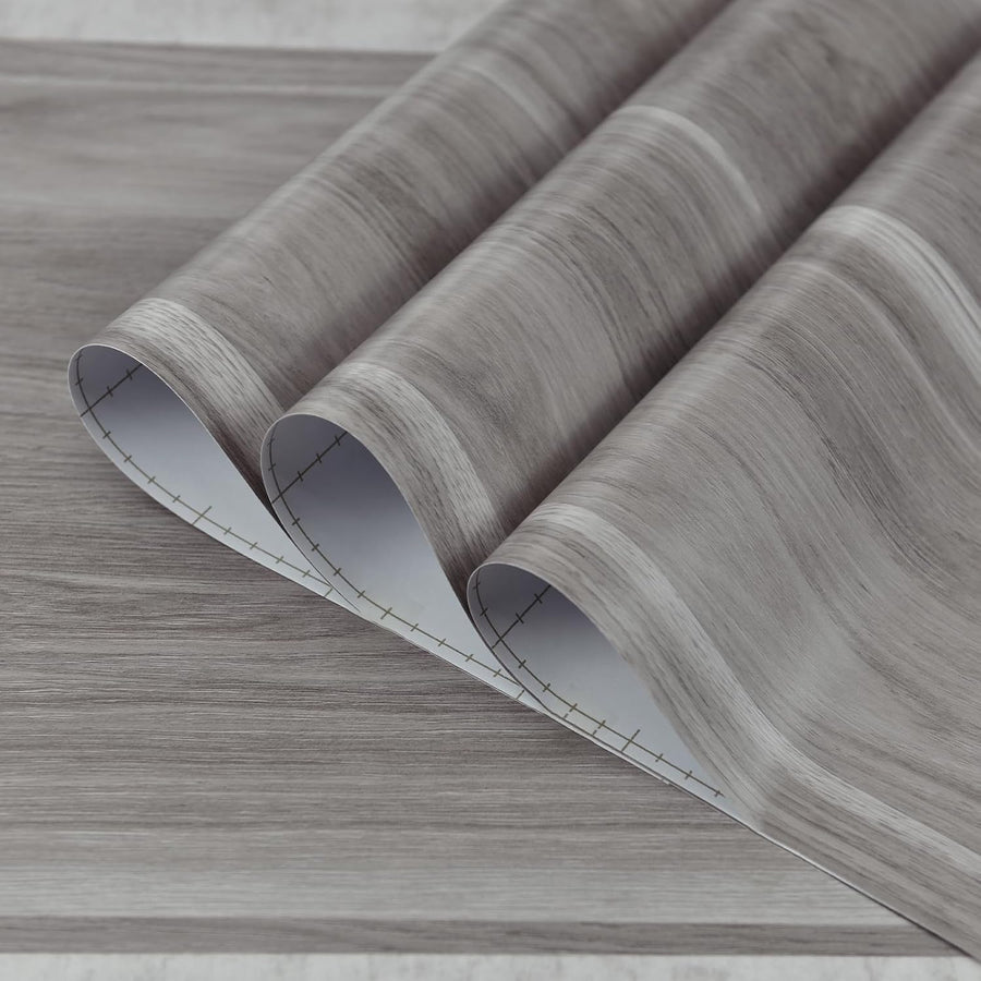 Rolls of gray wood-patterned vinyl flooring on a light gray background