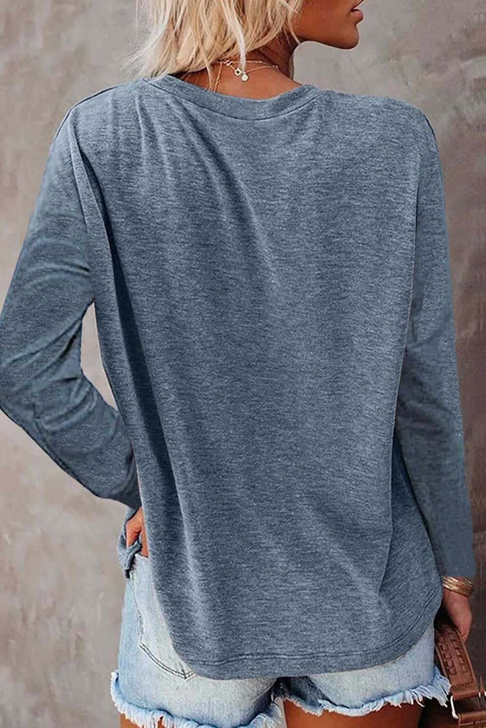 Person wearing a blue long-sleeve top with a neutral background