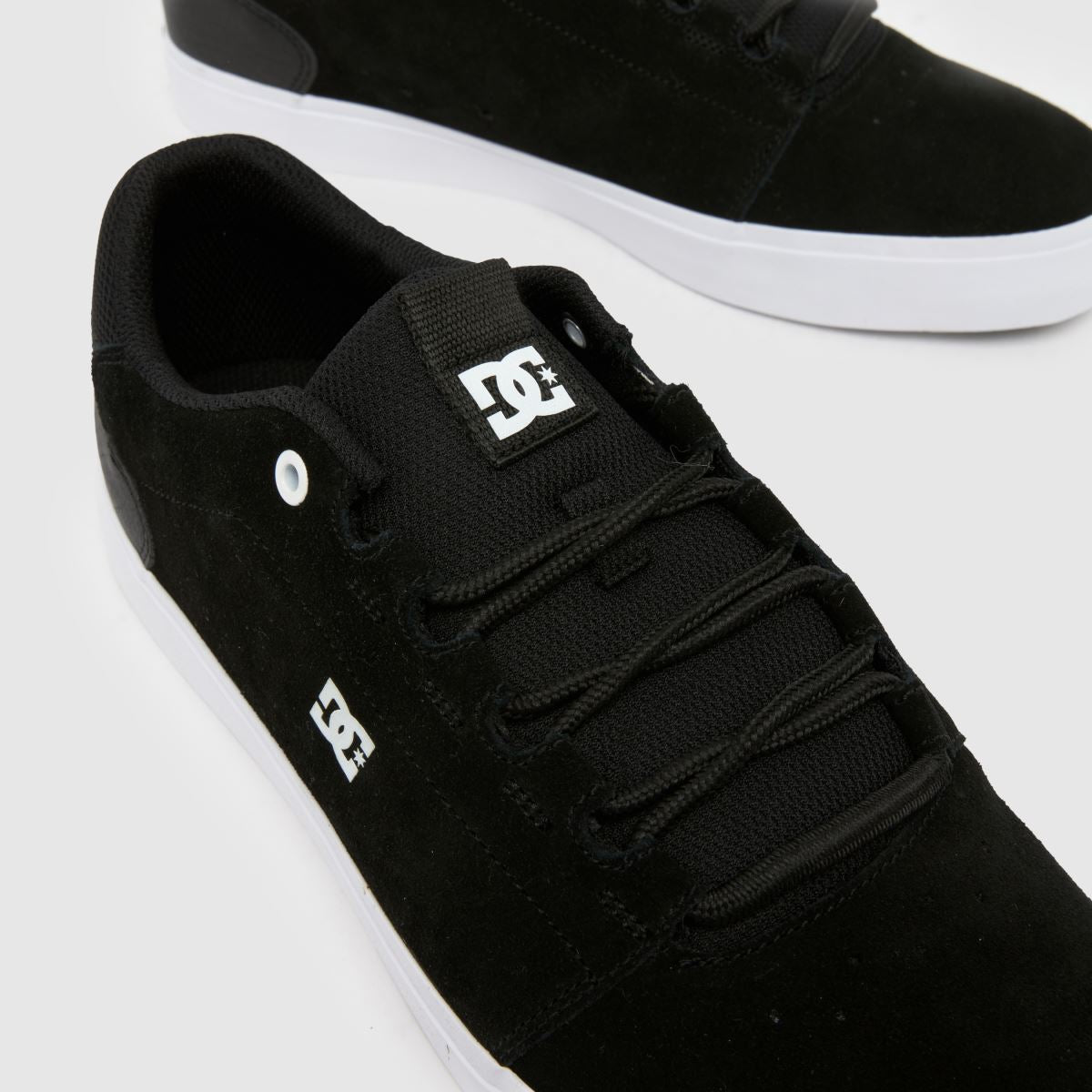 Black sneakers with white soles on a light gray background