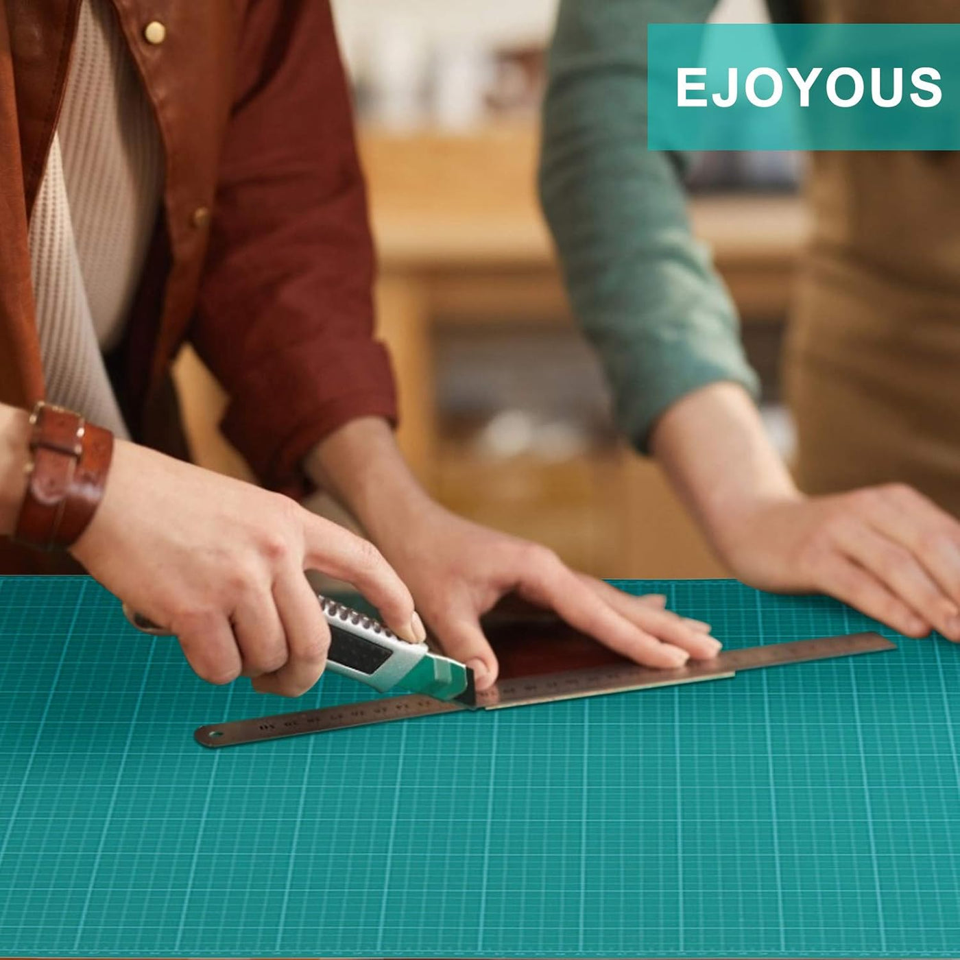 Two people measuring with a ruler on a green cutting mat, with 'EJOYOUS' branding visible.