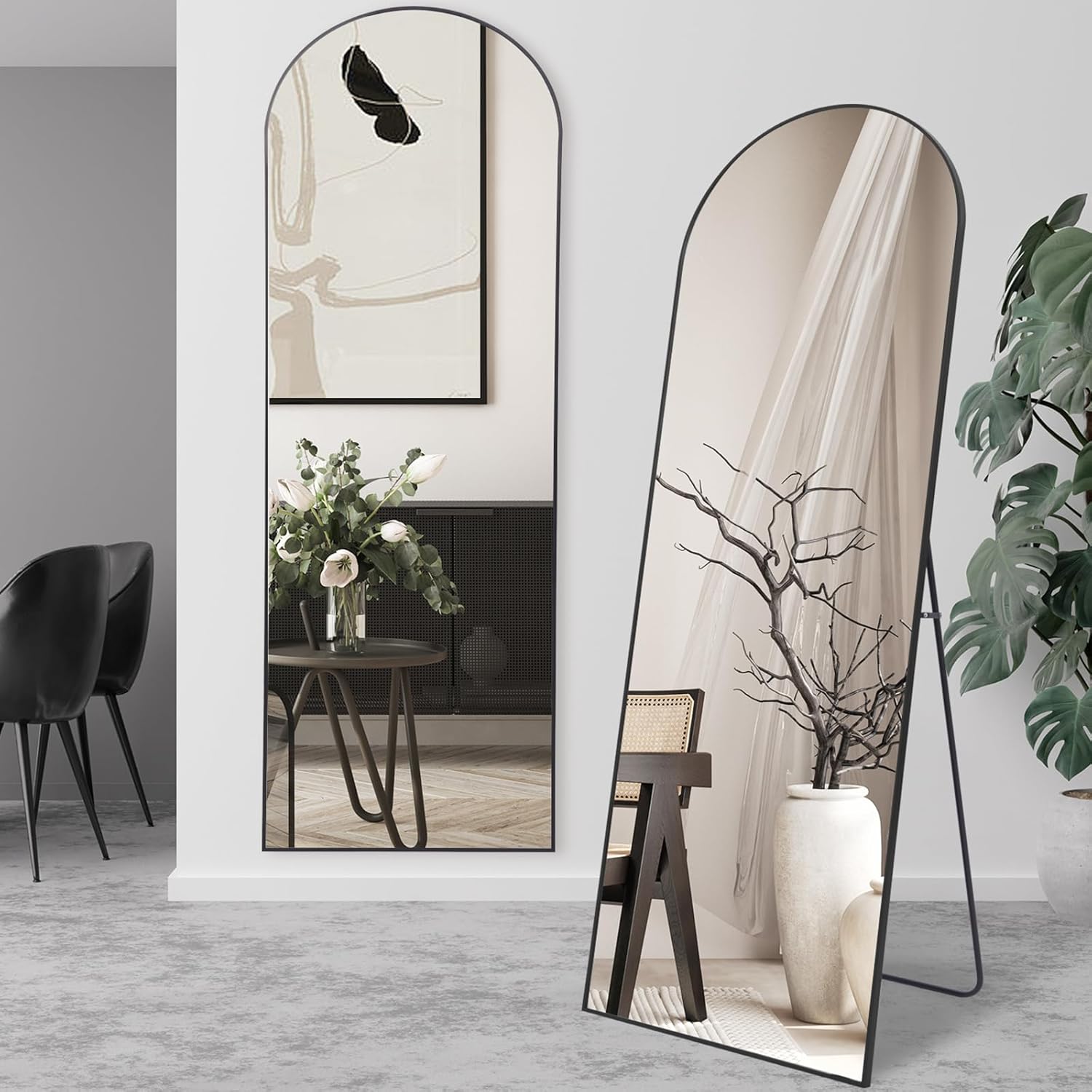 Two standing mirrors in a room with decor elements like a plant and vase.