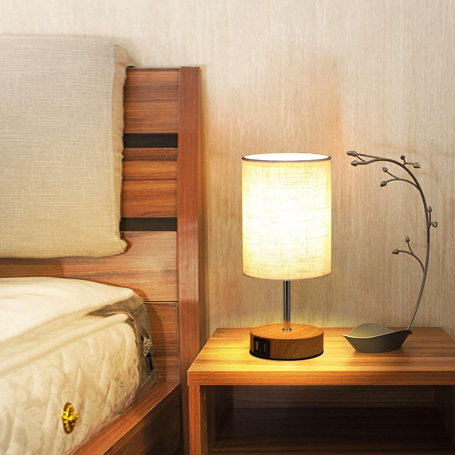 Bedroom scene with wooden bed and nightstand featuring a lit table lamp.