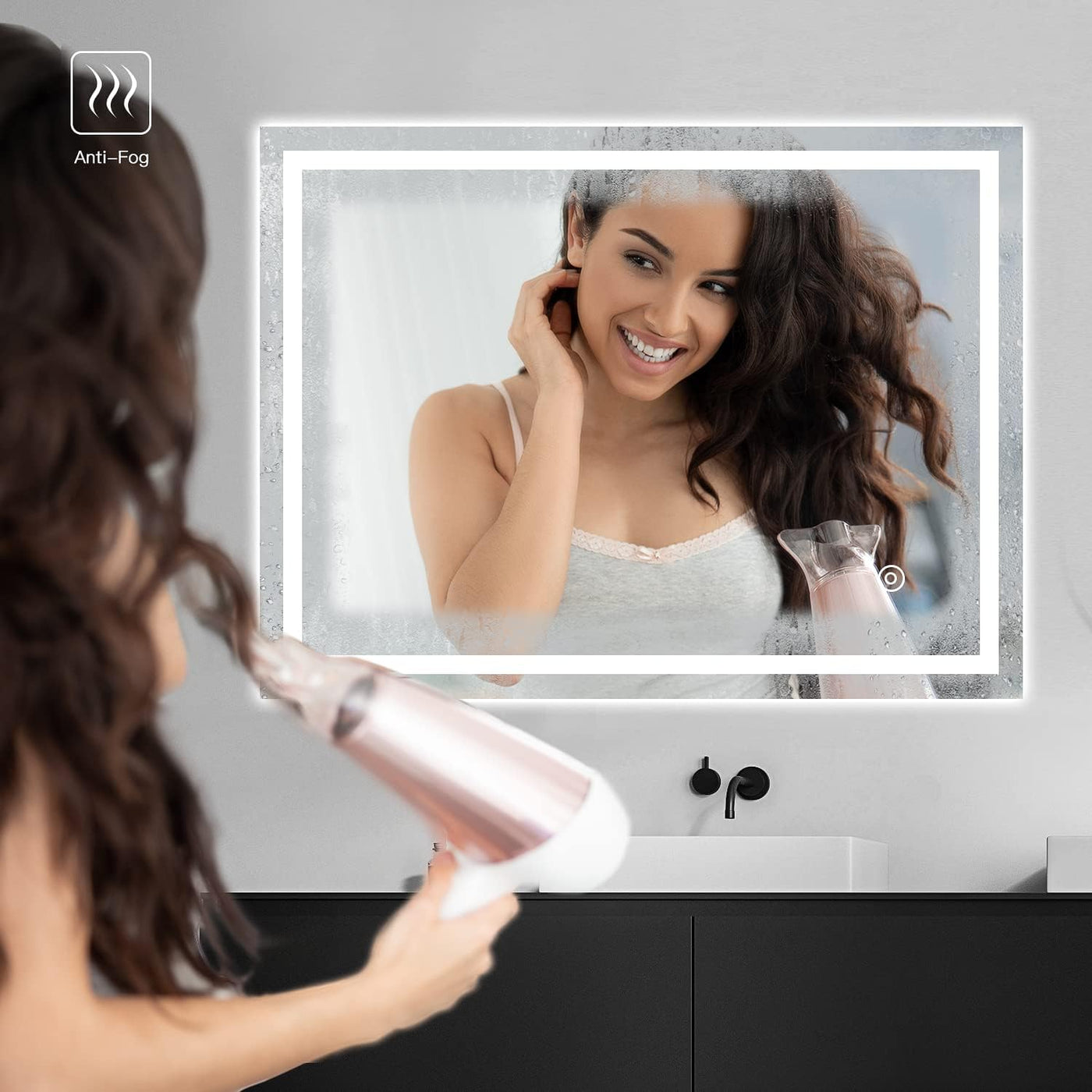 Woman using a hair dryer in front of an anti-fog bathroom mirror.