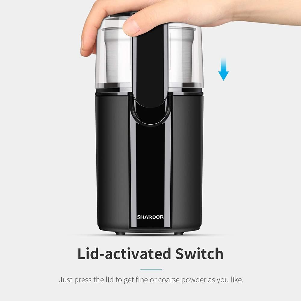 Black coffee grinder with a lid-activated switch on a white background