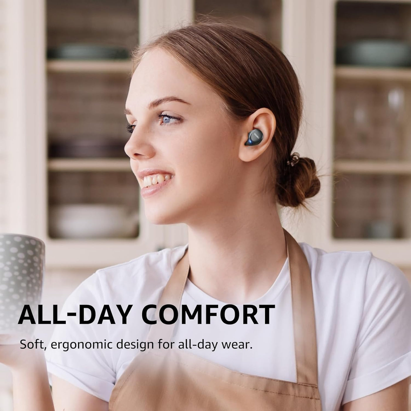 Woman wearing wireless earbuds with a kitchen background, emphasizing comfort.