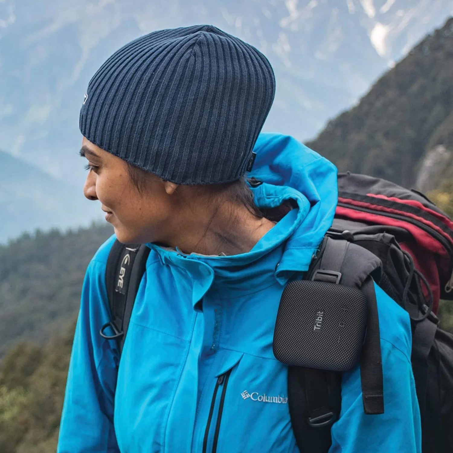 Person wearing a blue jacket and black beanie with a backpack in a mountainous area