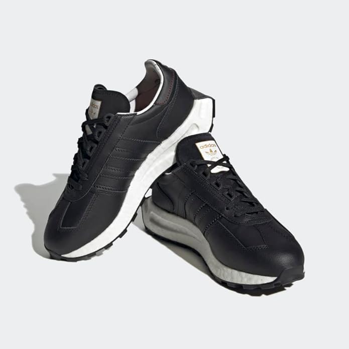 Black Adidas sneakers with white soles on a light gray background