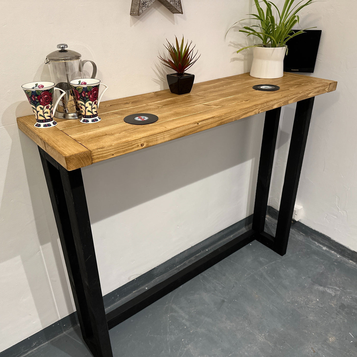 Wooden console table with black legs against a white wall