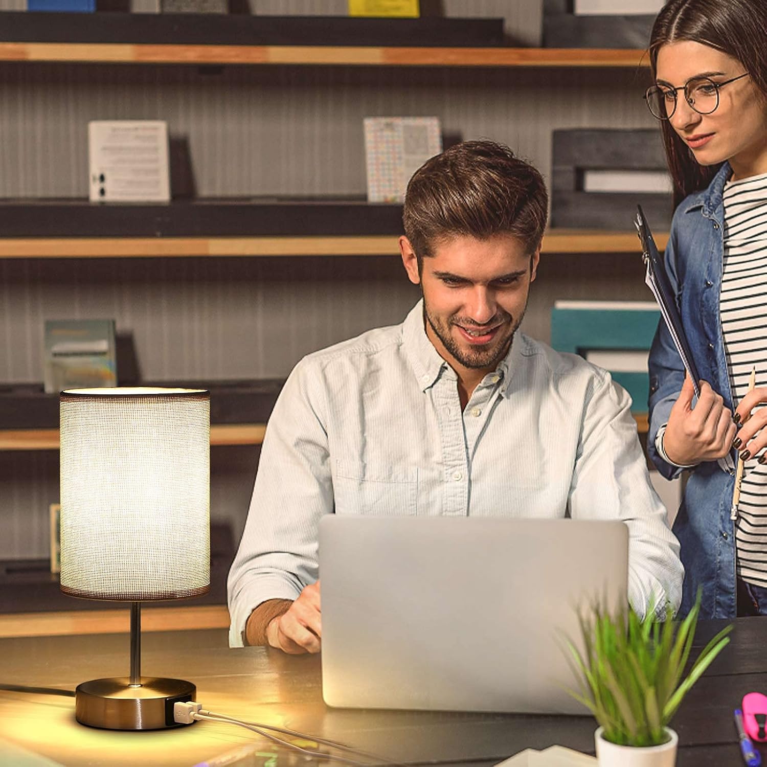 Two people working together on a laptop in a library setting