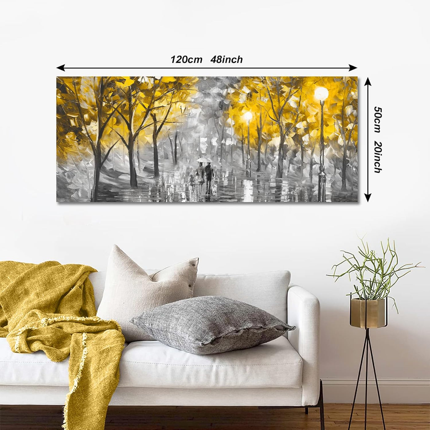 Wall art of a couple walking in a park with autumn trees, displayed above a white sofa.