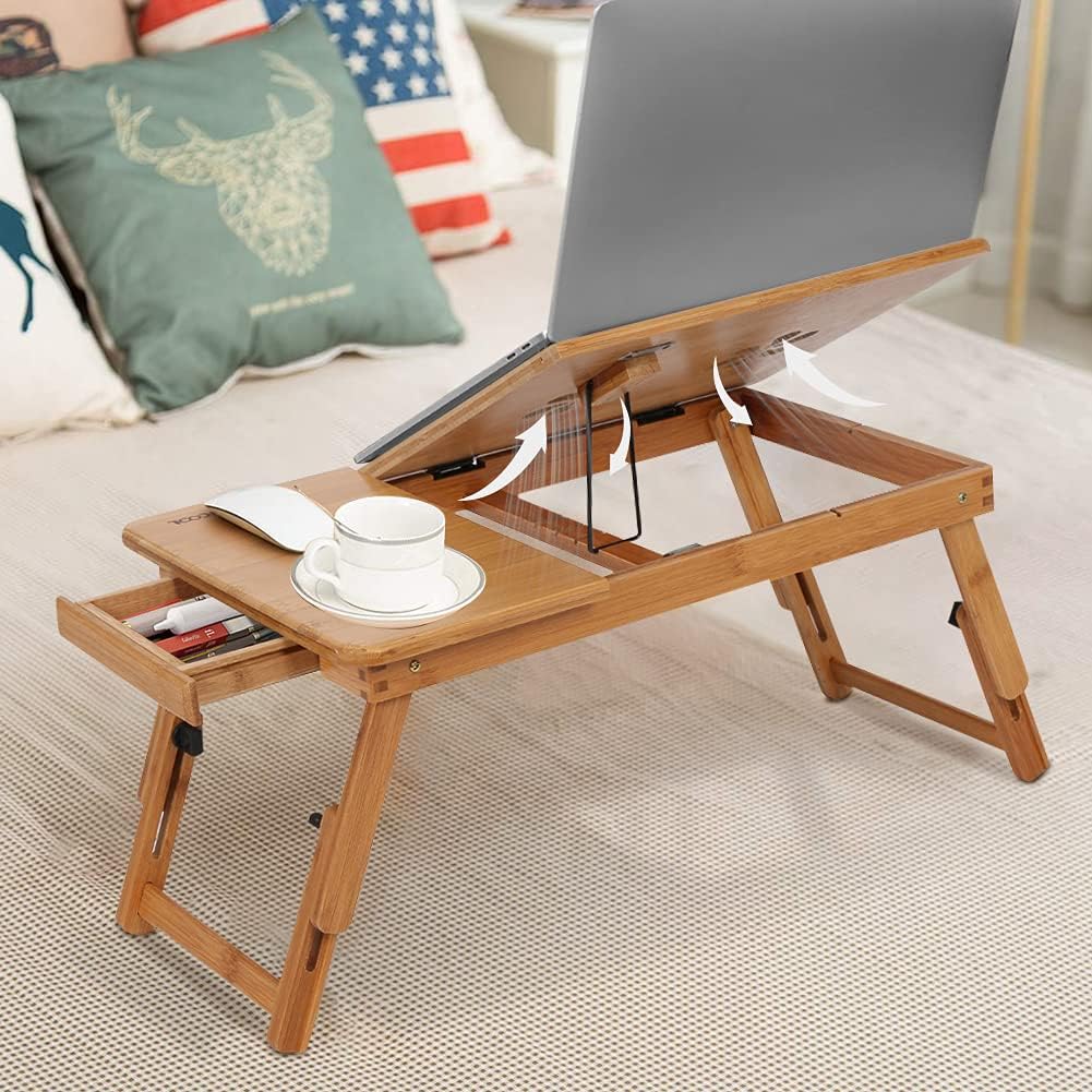 Wooden laptop desk with a cup and books on a bed