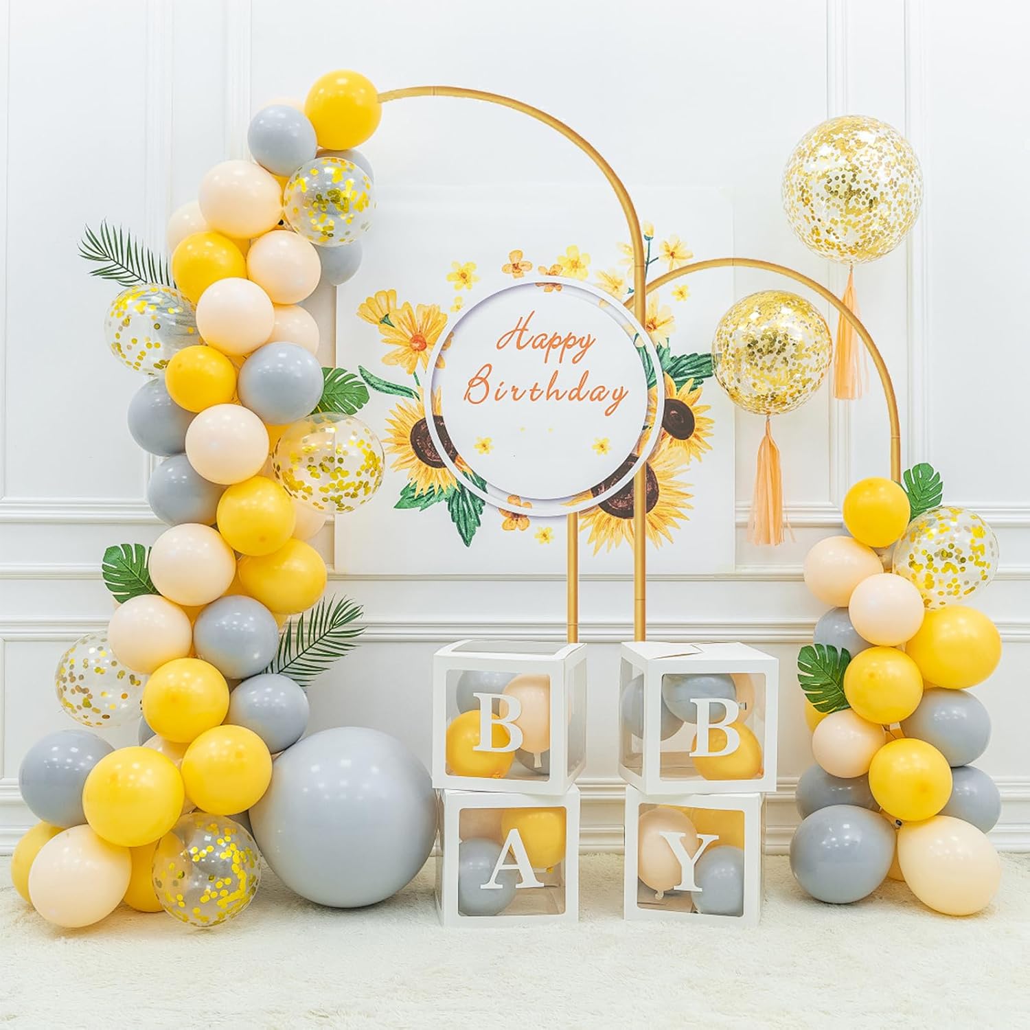 Birthday party setup with balloon arch, decorative sign, and baby-themed elements.