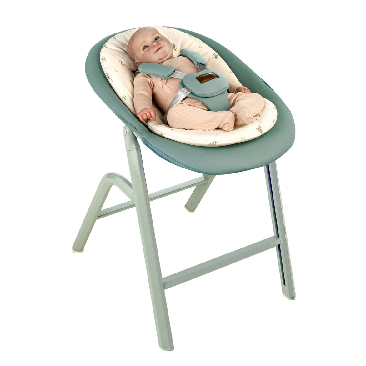 Baby in a green and beige baby seat on a white background