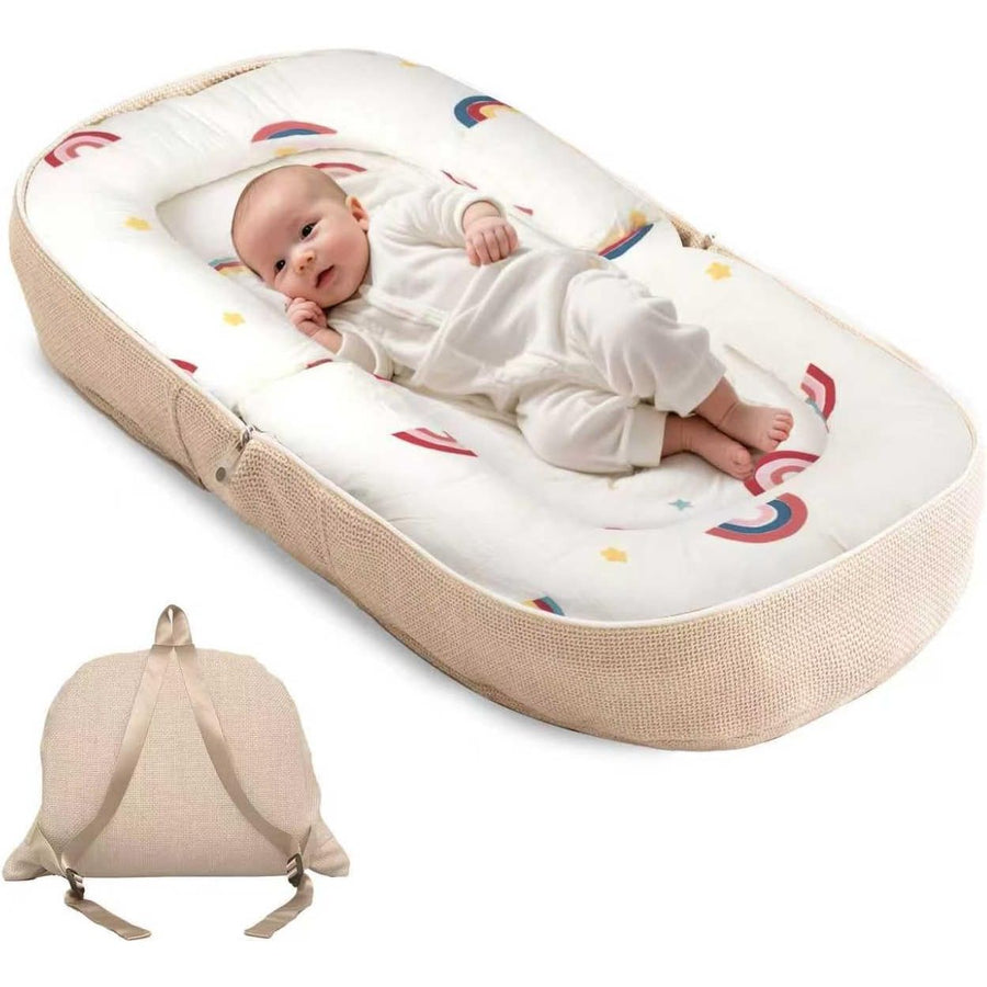 A baby sleep bassinet with a beige woven fabric exterior and a white interior printed with colorful rainbows and stars, shown with a baby lying inside and a smaller inset view of the bassinet folded flat with straps.