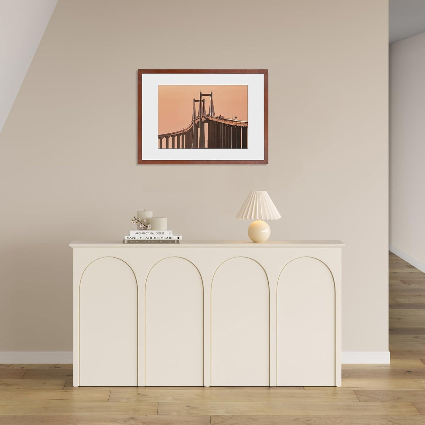 Framed picture of a bridge on a wall above a white cabinet with decor items.