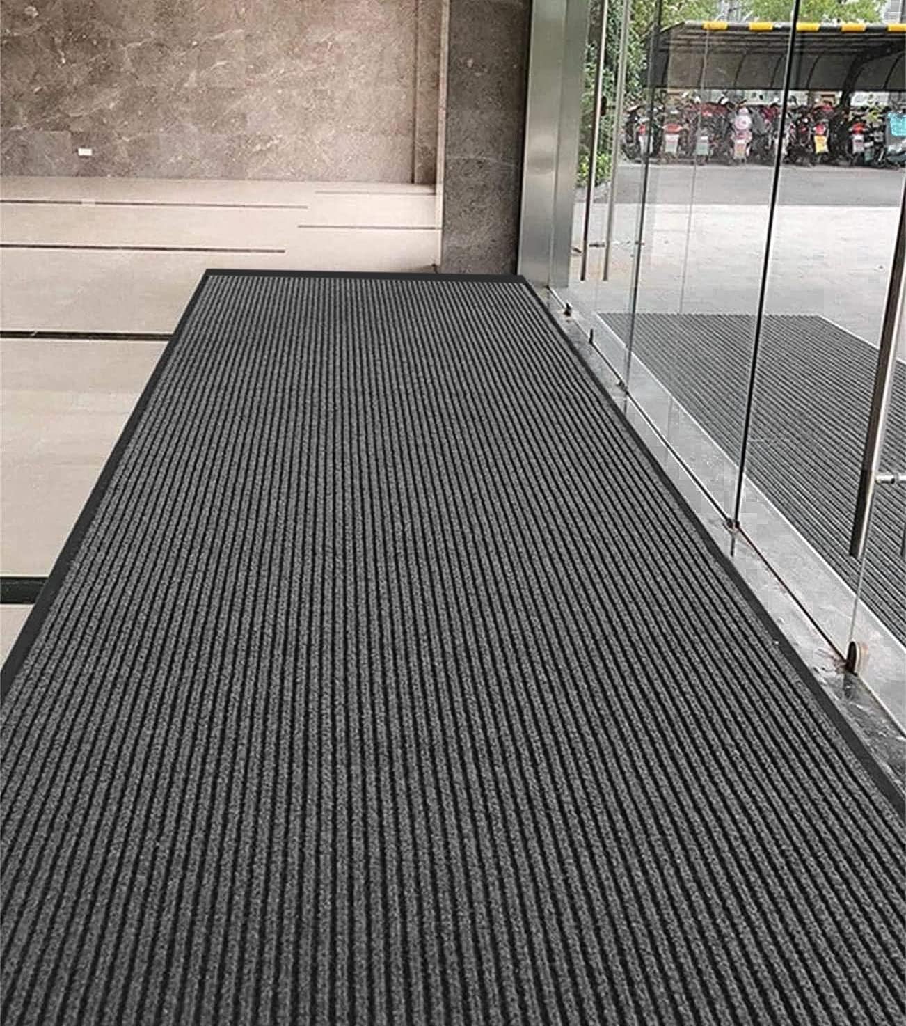 Textured black mat on a floor with glass walls and concrete wall in the background