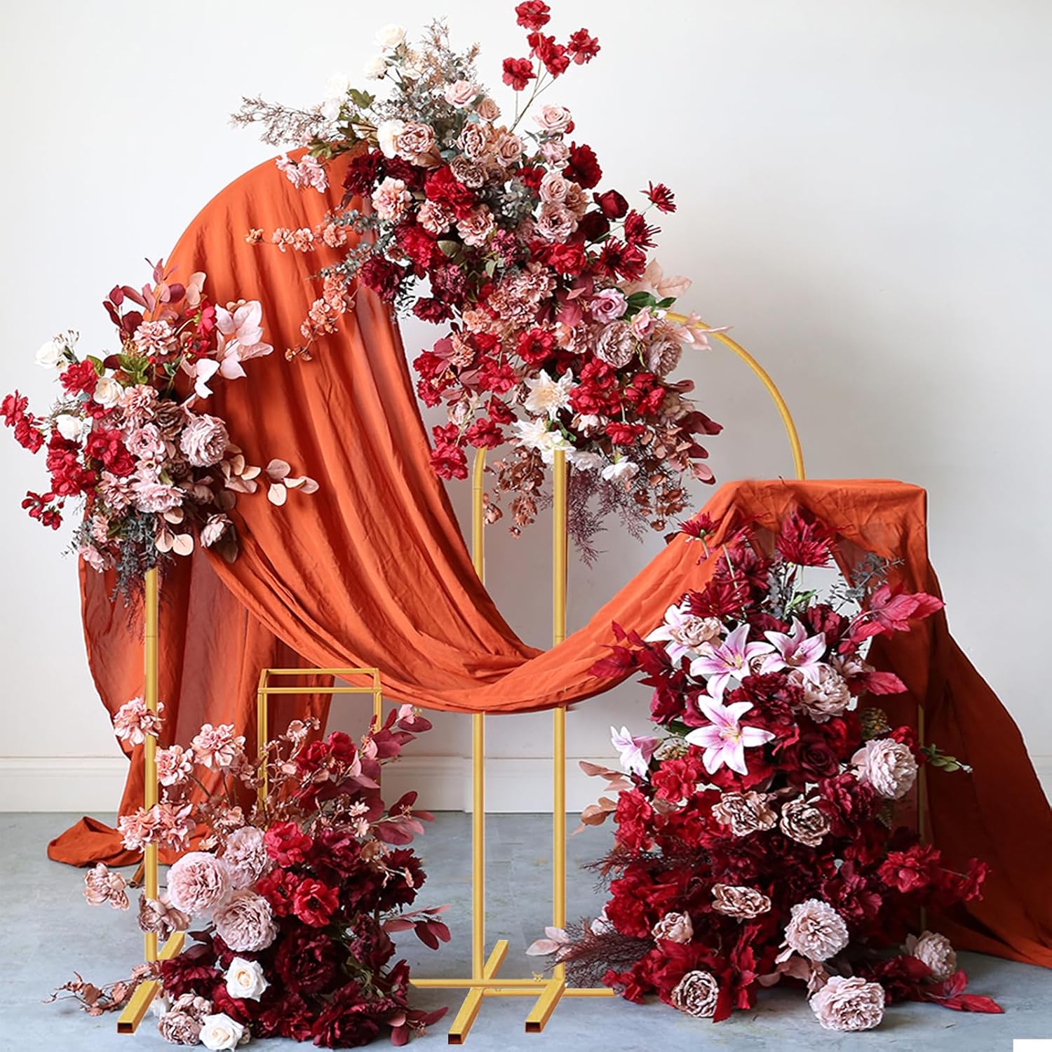 Decorative floral arrangement with red and pink flowers on a stand against a white background