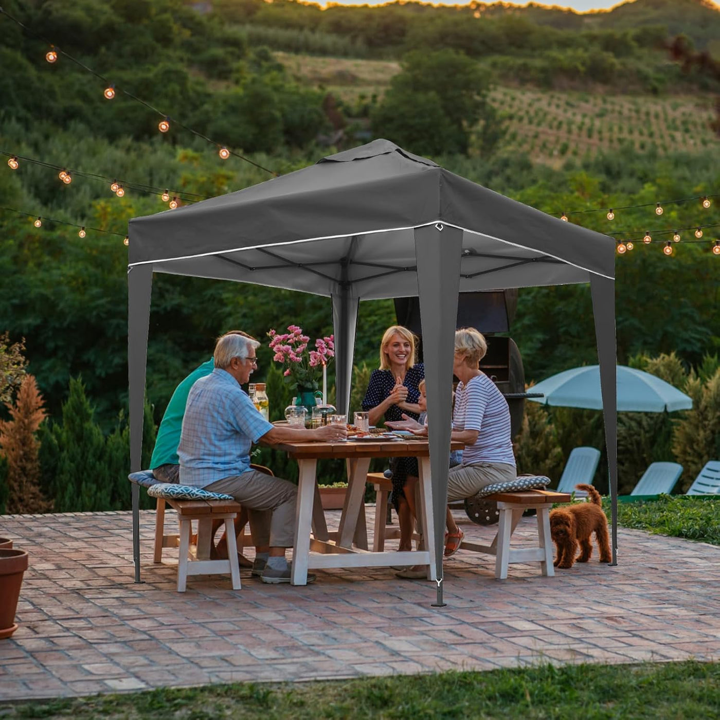 People sitting at a table under a gray outdoor canopy with a scenic background