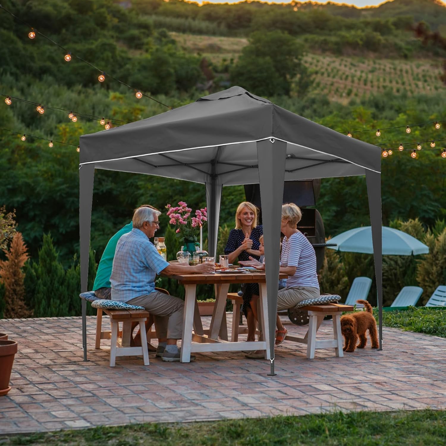 People sitting at a table under a gray outdoor canopy with a scenic background