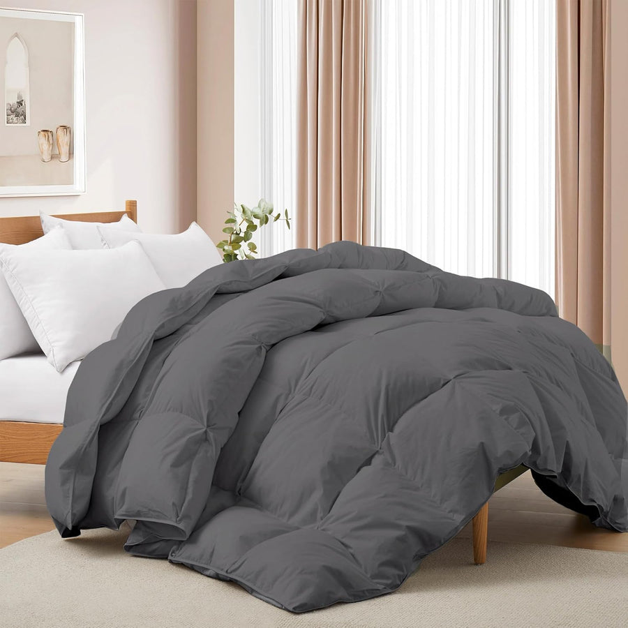 Gray comforter on a bed in a bedroom setting with white bedding and curtains.