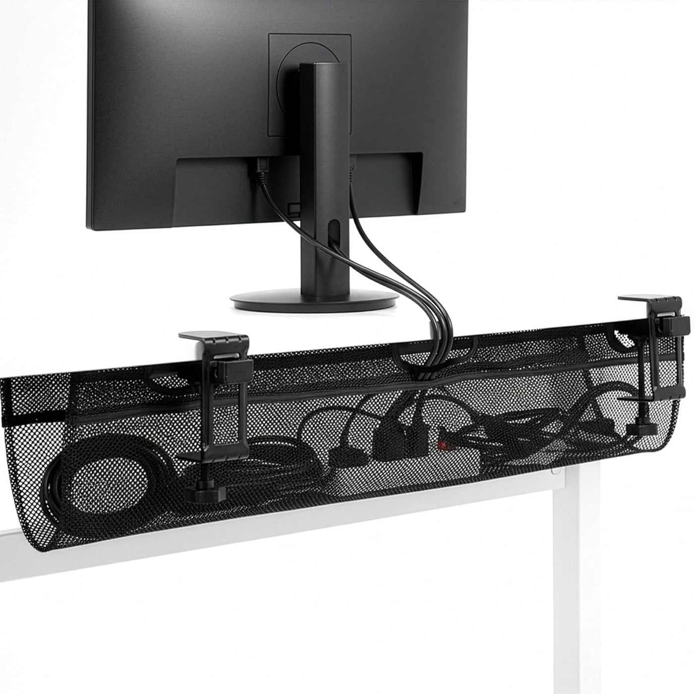Black mesh cable organizer under a computer monitor on a white surface