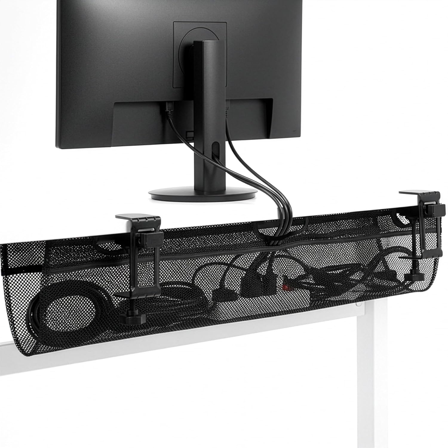 Black mesh cable organizer under a computer monitor on a white surface