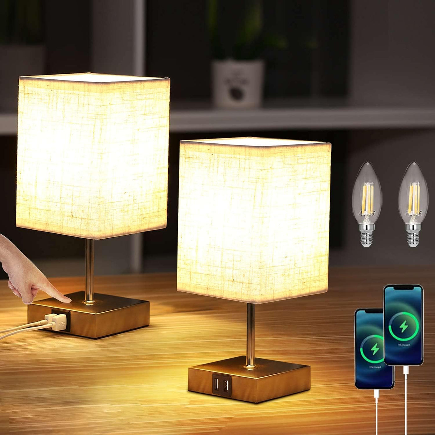 Two table lamps with a hand plugging in a device, two light bulbs, and two smartphones on a wooden surface.