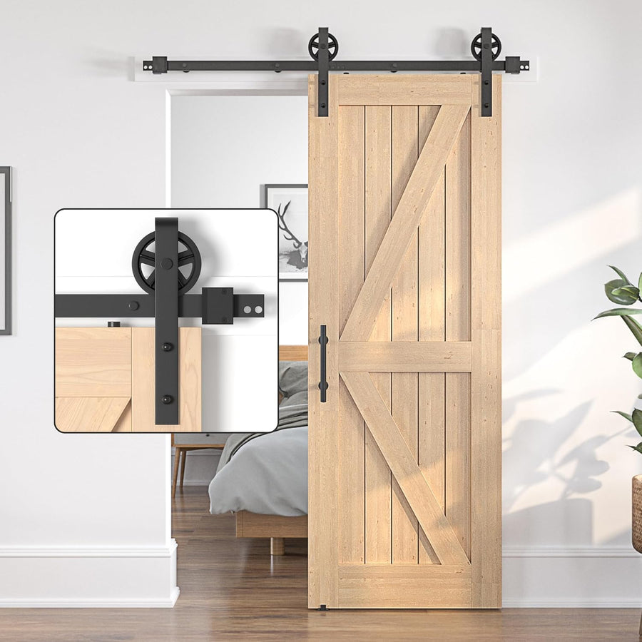 Wooden sliding barn door with black metal hardware in a room setting.