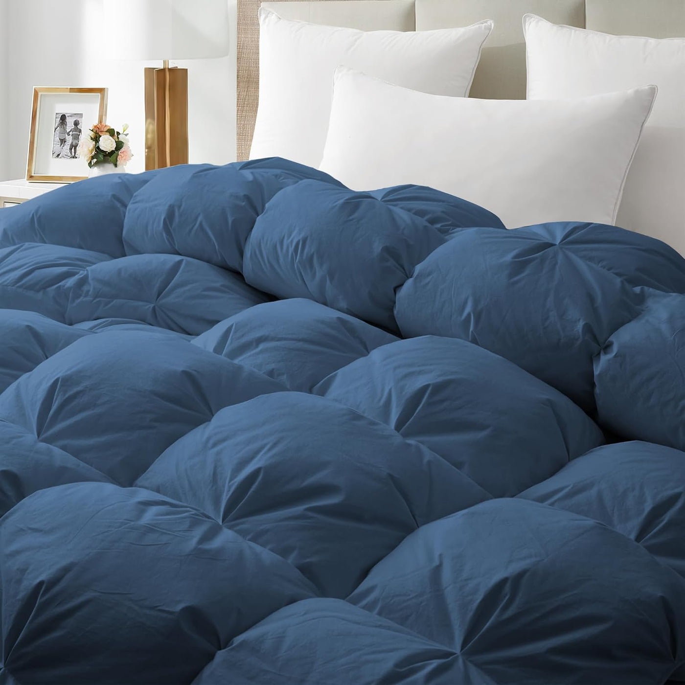 Blue comforter on a bed with white pillows in a bedroom setting