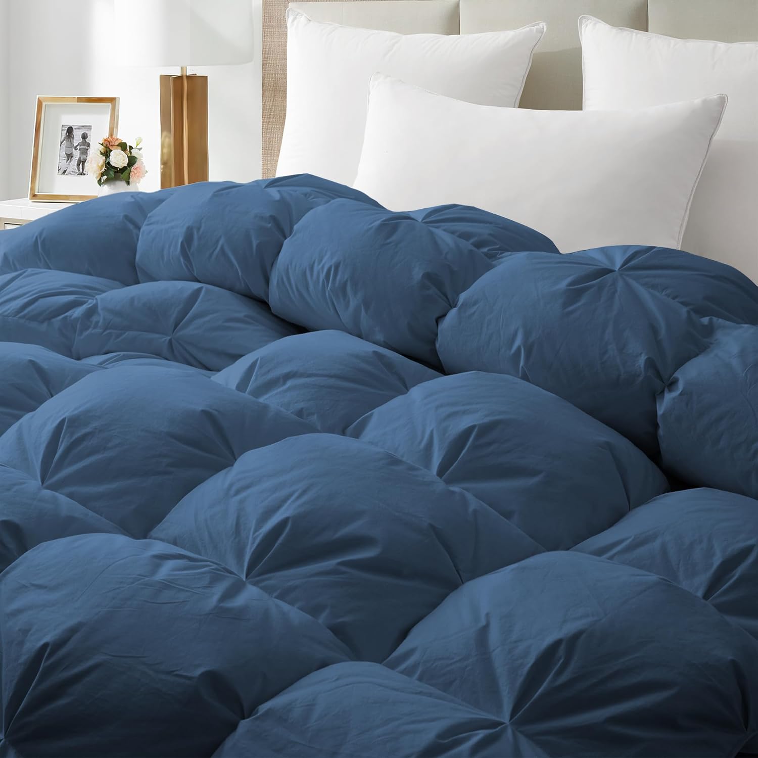 Blue comforter on a bed with white pillows in a bedroom setting